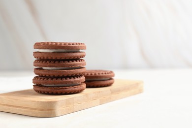 Tasty chocolate sandwich cookies with cream on light table, space for text