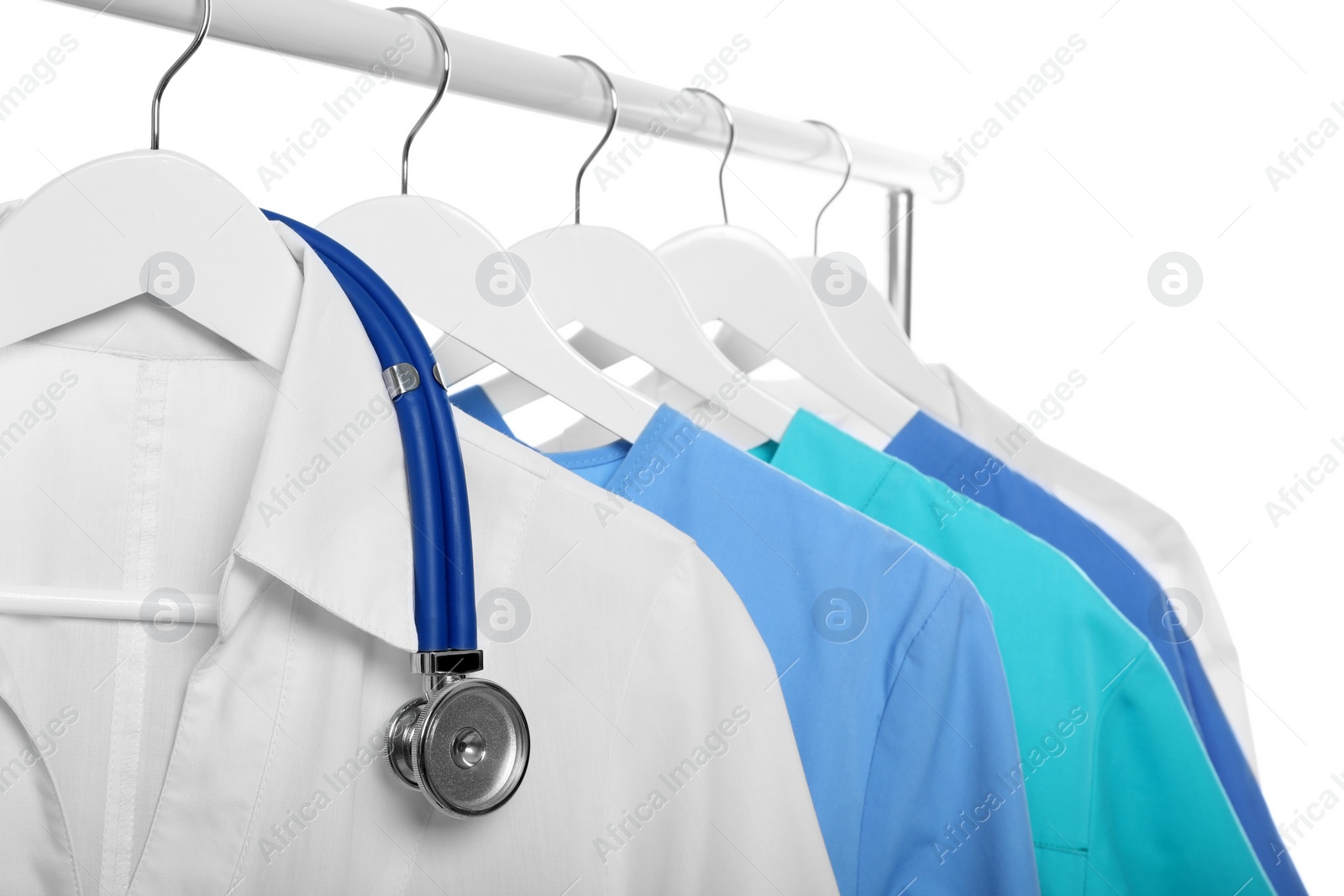 Photo of Doctor's gown with stethoscope and different medical uniforms on rack against white background