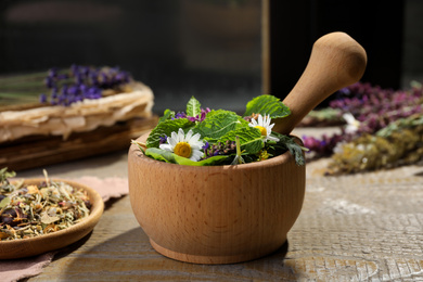 Photo of Mortar with healing herbs and pestle on wooden table