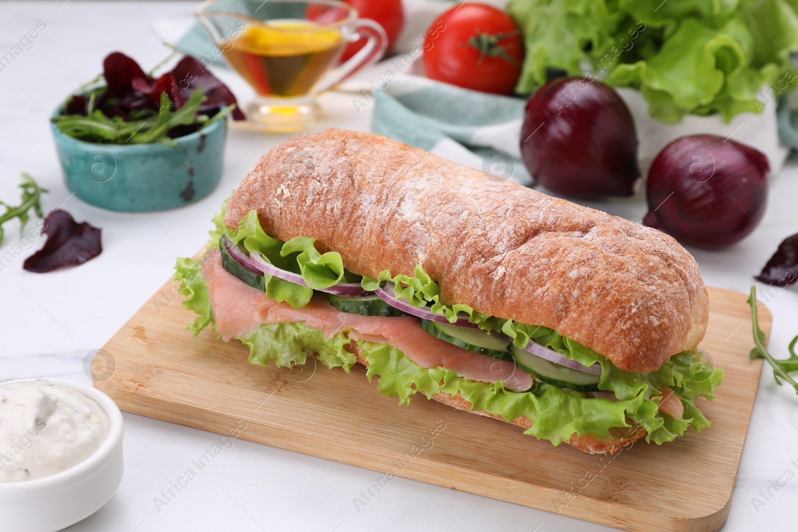 Photo of Delicious sandwich with fresh vegetables and salmon on white table, closeup