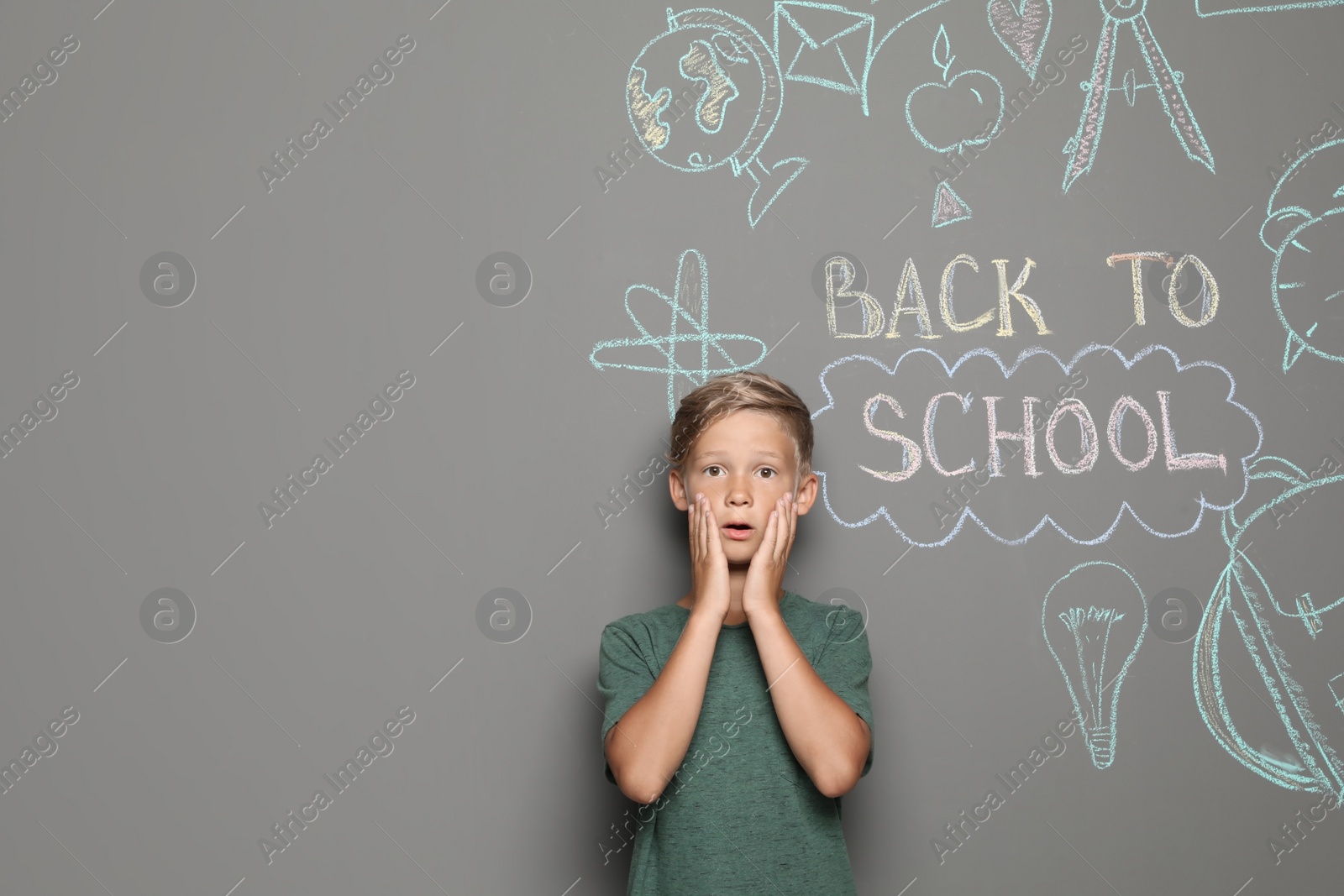 Photo of Little child near drawings and text BACK TO SCHOOL on grey background