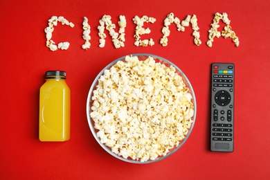 Flat lay composition with popcorn, TV remote and word CINEMA on color background