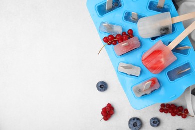 Photo of Flat lay composition with mold and berry ice pops on light table. Space for text