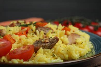 Photo of Delicious pilaf with meat and tomatoes on plate, closeup