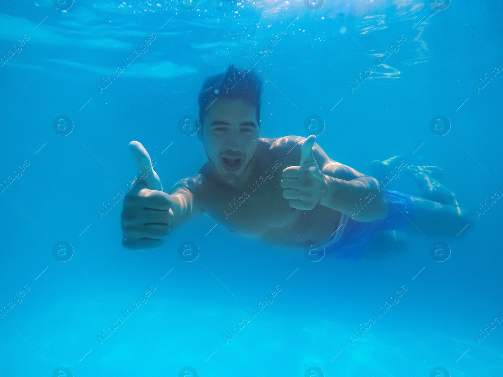 Photo of Handsome young man swimming in pool, underwater view