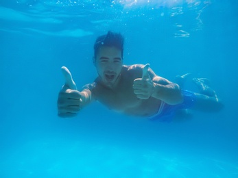 Handsome young man swimming in pool, underwater view