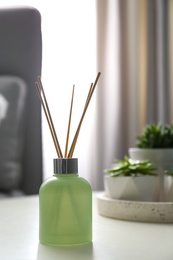 Photo of Aromatic reed air freshener on white table in room