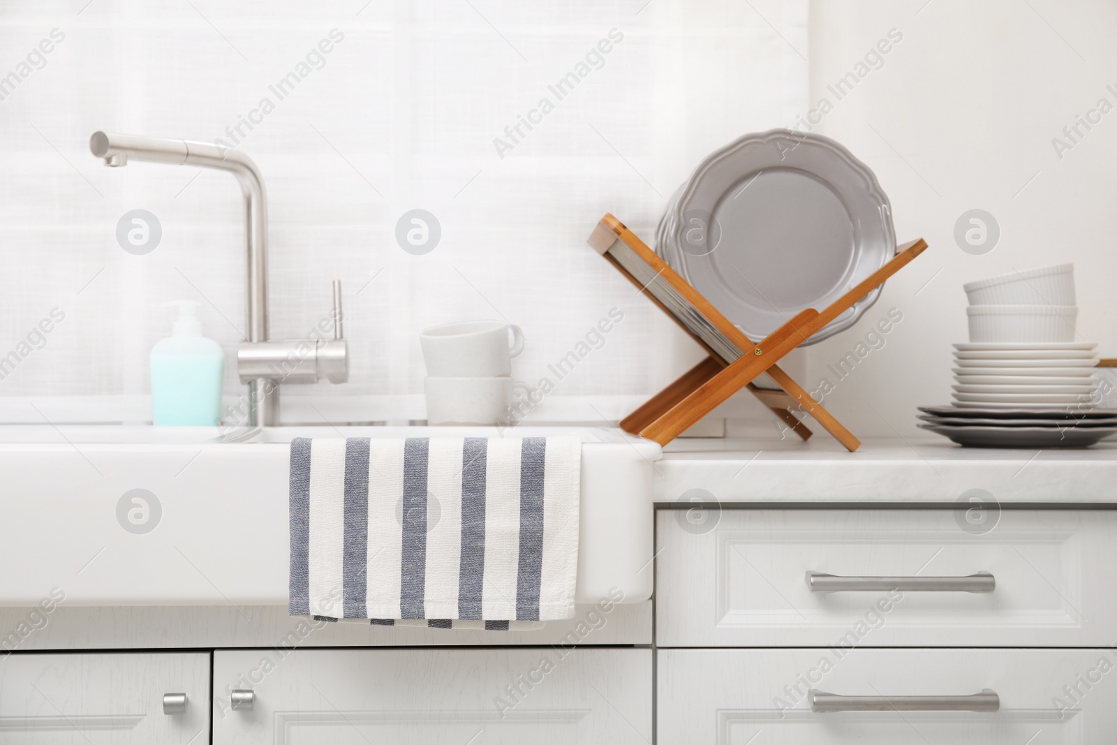 Photo of Clean dishes on wooden drying rack in stylish kitchen
