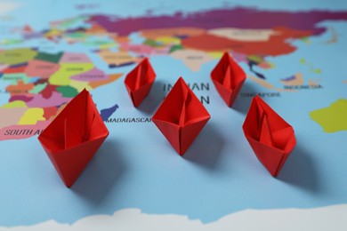 Red paper boats on world map, closeup