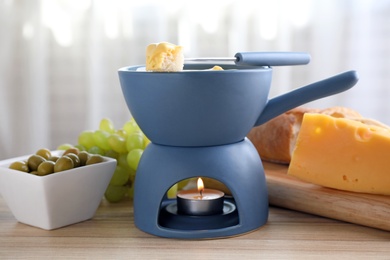 Photo of Pot of tasty cheese fondue and products on table