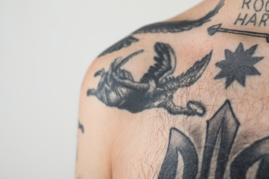 Photo of Young man with tattoos on body against white background, closeup