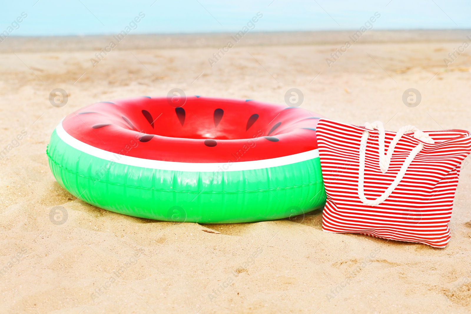 Photo of Colorful inflatable ring and bag on sand. Beach object