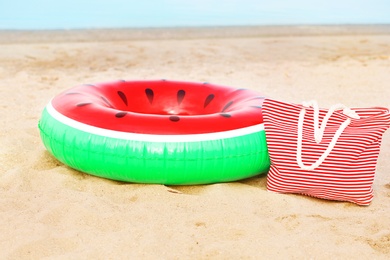 Photo of Colorful inflatable ring and bag on sand. Beach object