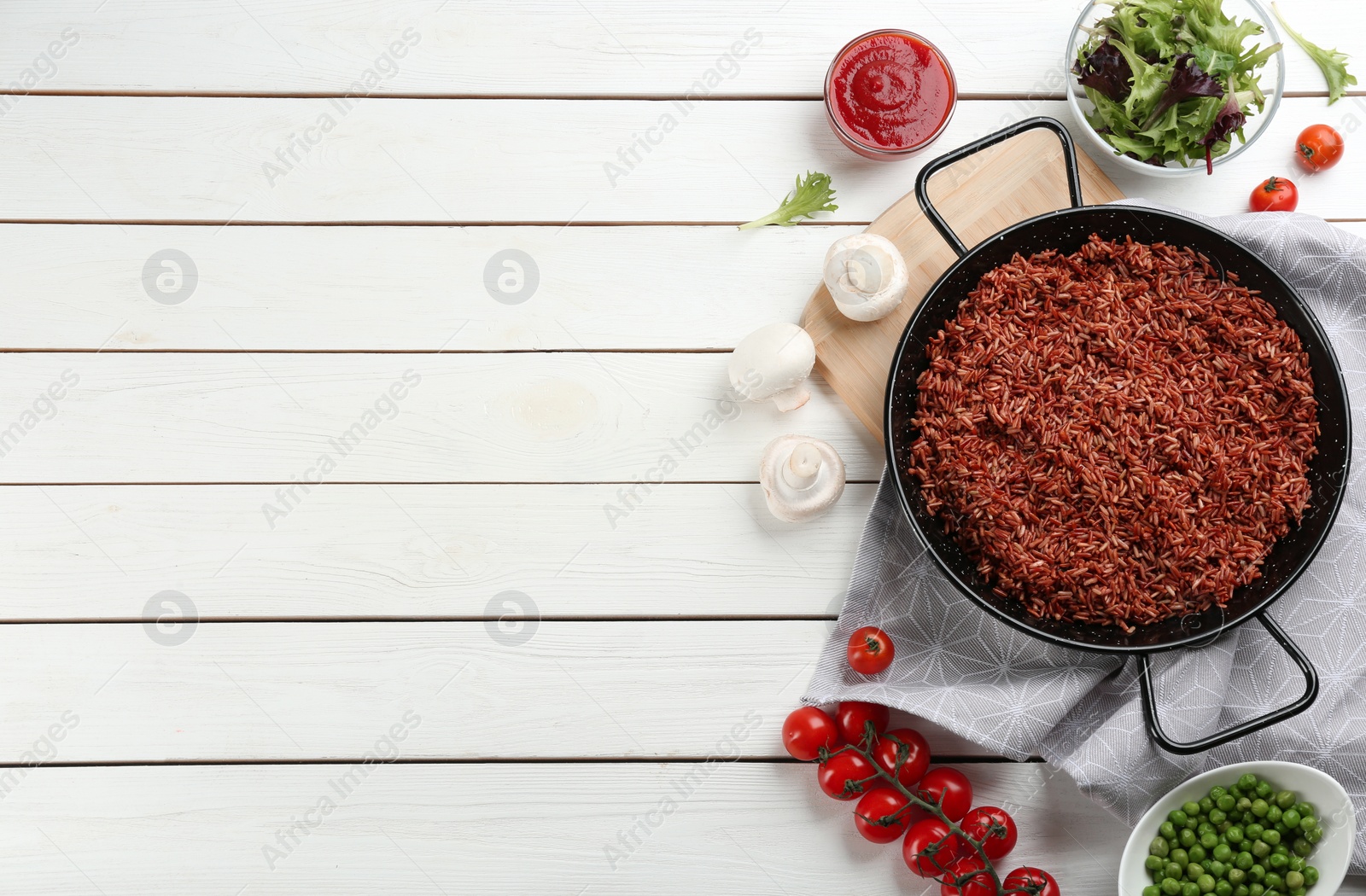 Photo of Tasty brown rice served on white wooden table, flat lay. Space for text