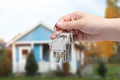 Woman holding keys near house outdoors, closeup