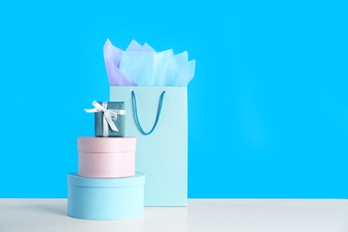 Photo of Gift bag and boxes on white table against light blue background. Space for text