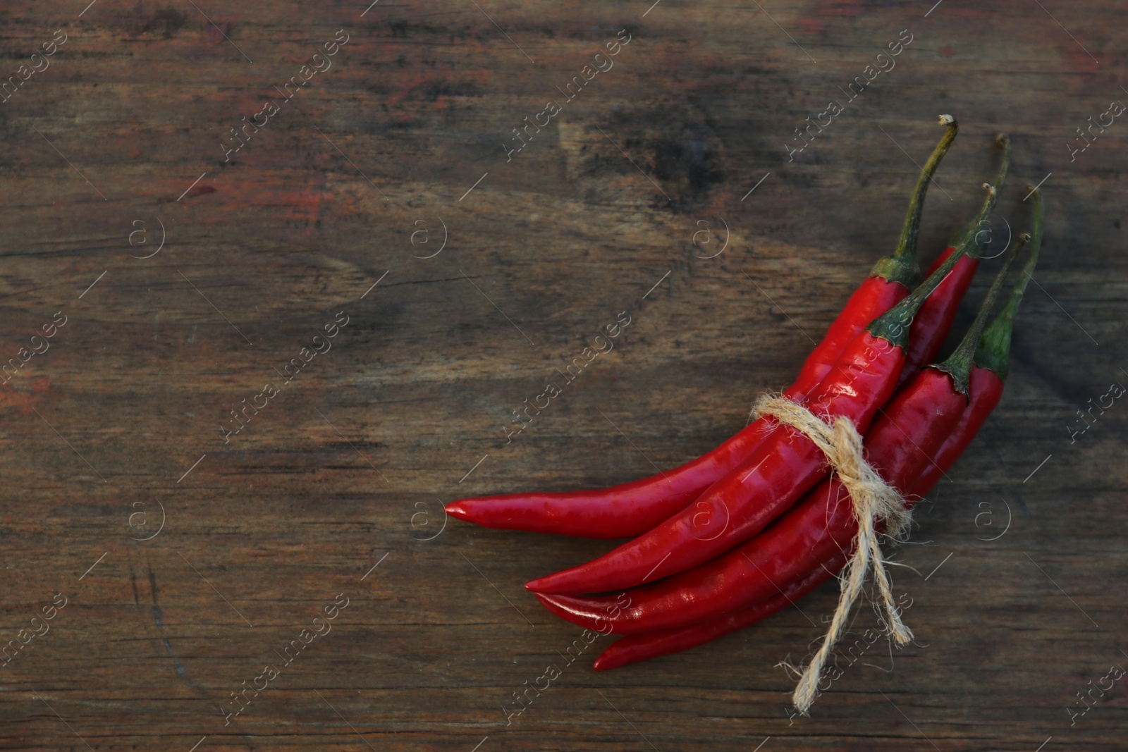 Photo of Fresh ripe chili peppers on wooden table, top view. Space for text
