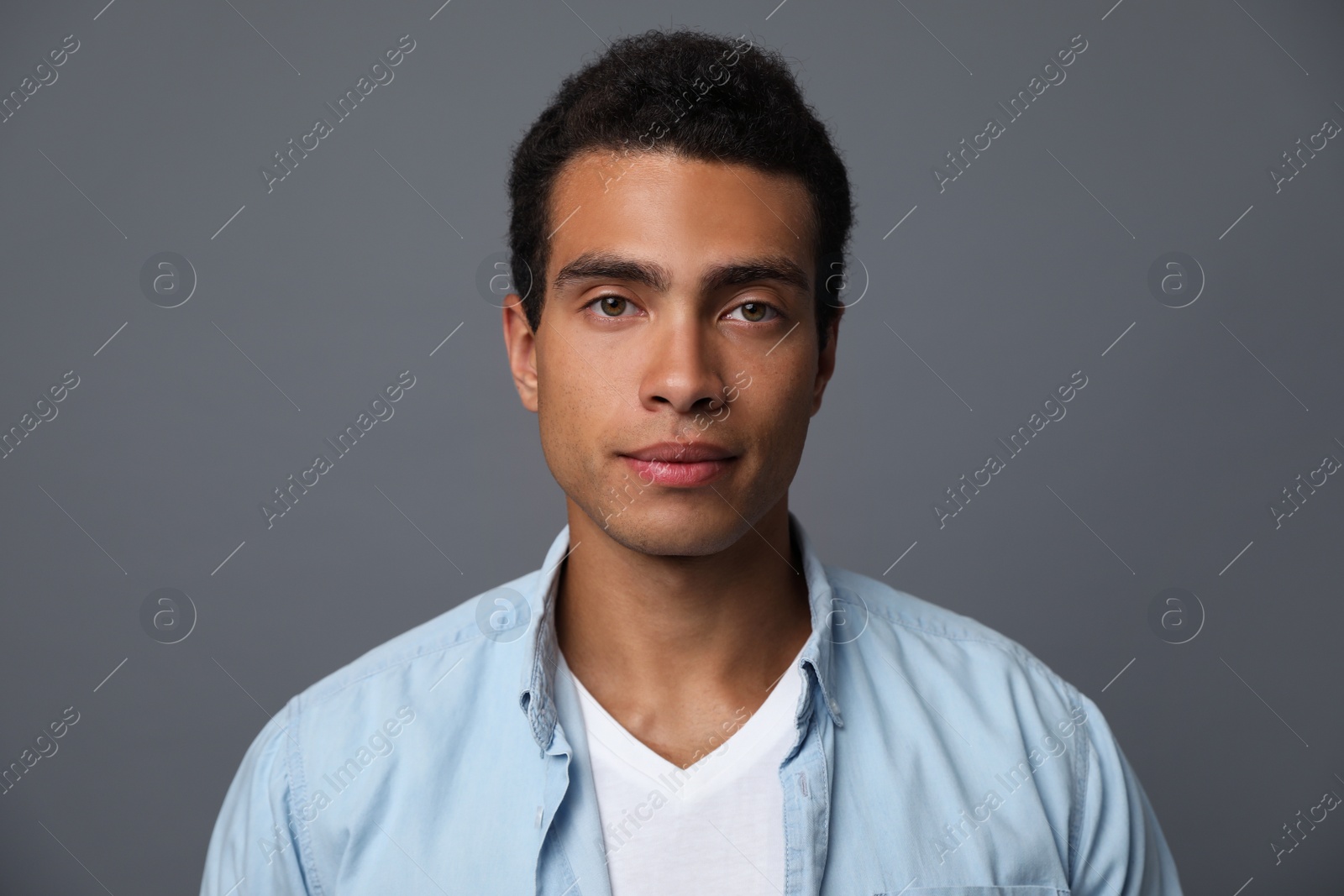 Photo of Handsome young African-American man on grey background