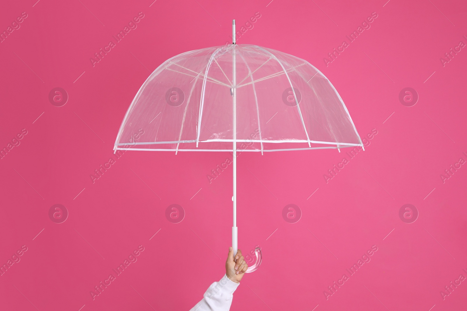 Photo of Woman with open transparent umbrella on pink background, closeup