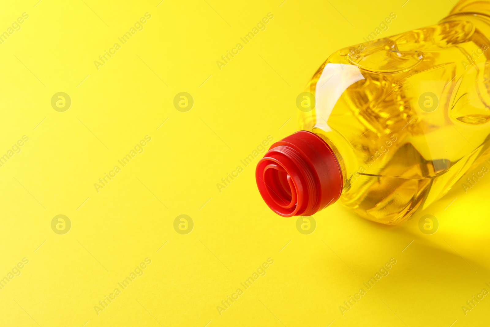 Photo of Plastic bottle of cooking oil on yellow background. Space for text