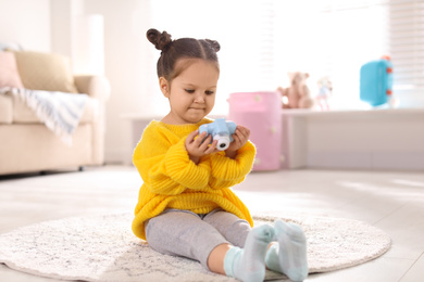 Little photographer with toy camera on floor at home