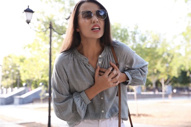 Young woman having heart attack in park