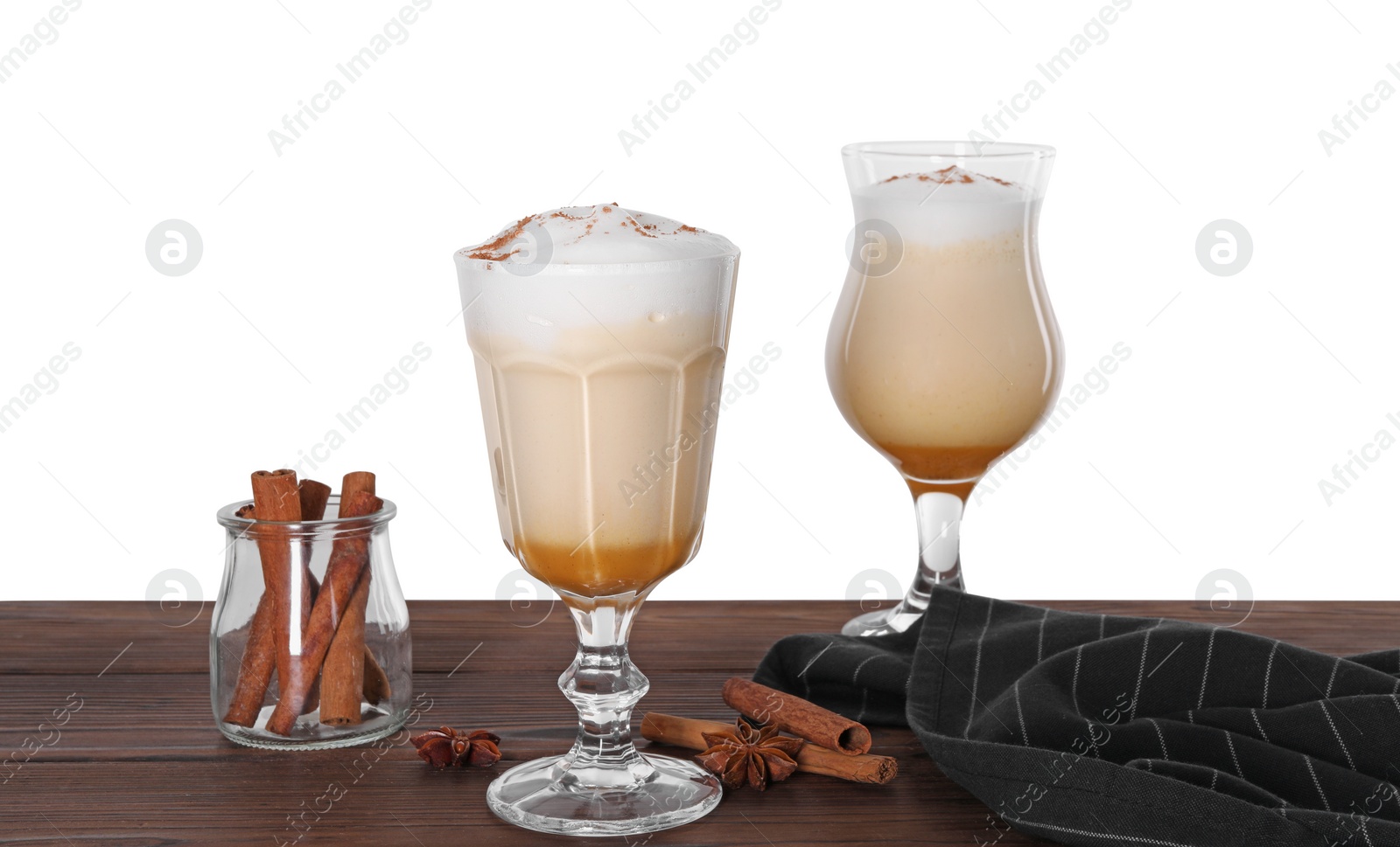 Photo of Delicious eggnog in glasses and spices on wooden table against white background