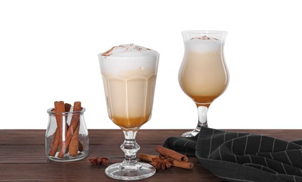 Photo of Delicious eggnog in glasses and spices on wooden table against white background