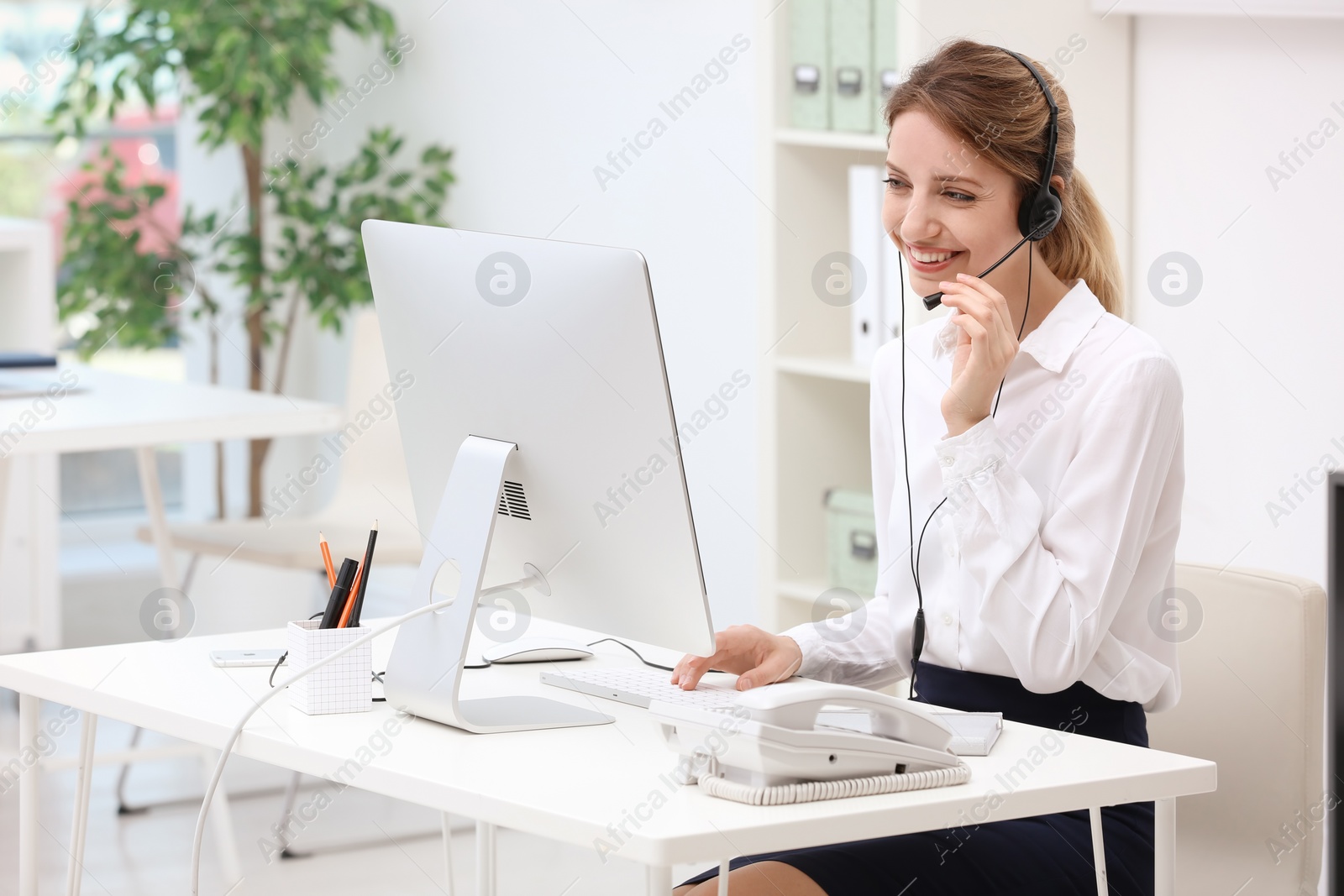 Photo of Female receptionist with headset at desk in office