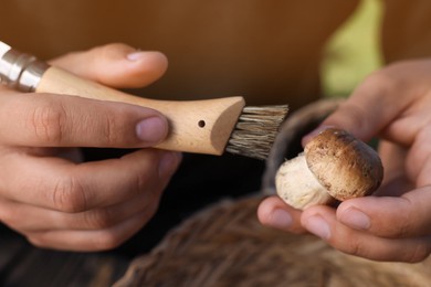 Photo of Man cleaning mushroom with brush, closeup view