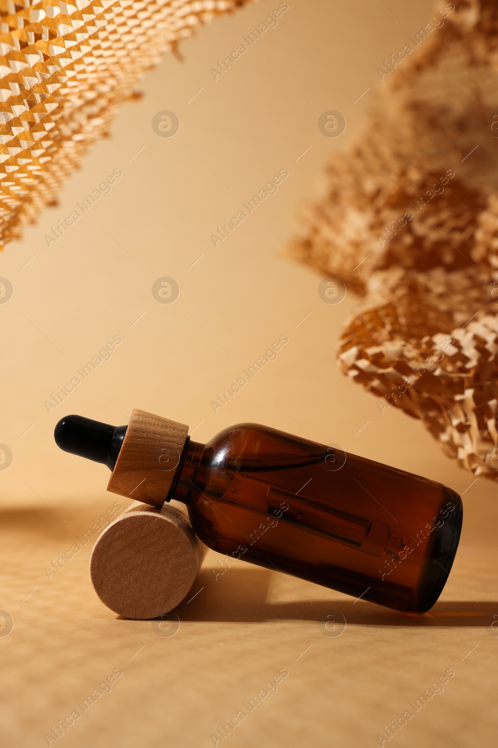 Photo of Glass bottle of essential oil on dark beige background