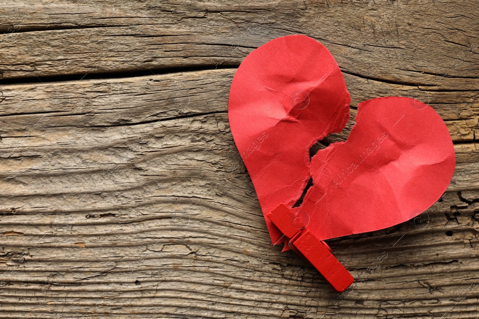 Photo of Broken heart. Torn red paper heart with clothespin on wooden table, top view. Space for text