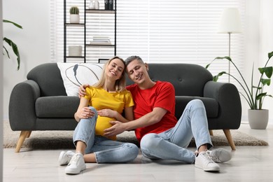 Photo of Young family housing concept. Pregnant woman with her husband on floor at home
