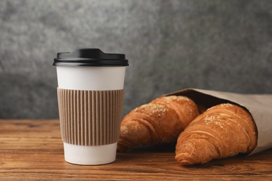 Photo of Coffee to go. Paper cup with tasty drink and pastry on wooden table