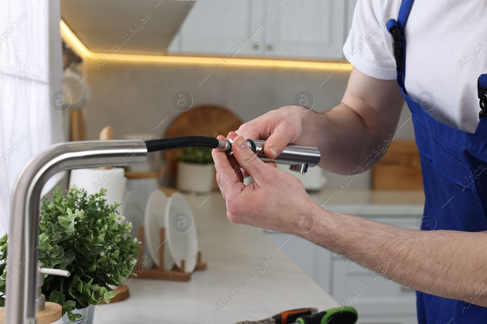 Photo of Plumber examining metal faucet in kitchen, closeup