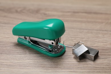Photo of Turquoise stapler and staples on wooden table