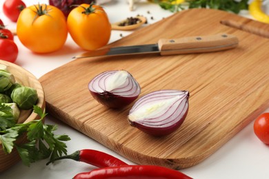 Photo of Cutting board with different vegetables and knife on white wooden table, closeup