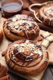 Delicious rolls with toppings and nuts on wooden table, closeup. Sweet buns