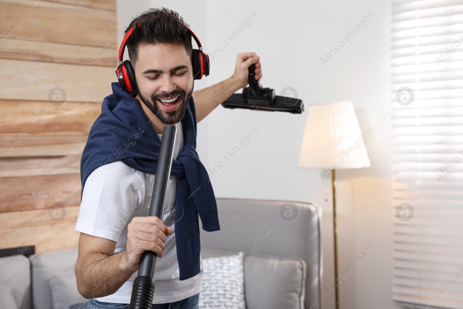 Photo of Young man having fun while vacuuming at home