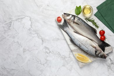 Photo of Sea bass fish and ingredients on white marble table, flat lay. Space for text