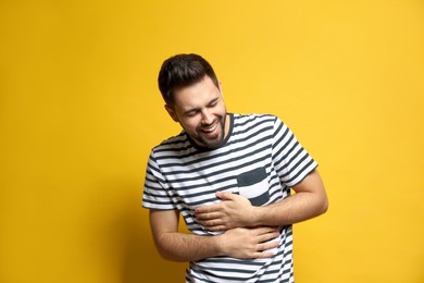 Photo of Young man laughing on yellow background. Funny joke