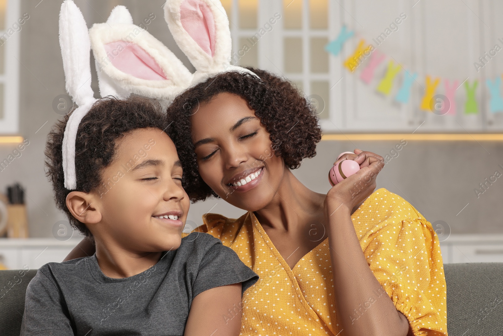Photo of Happy African American mother with Easter eggs and her cute son indoors