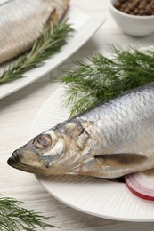 Photo of Delicious salted herrings, dill and onion on white wooden table, closeup