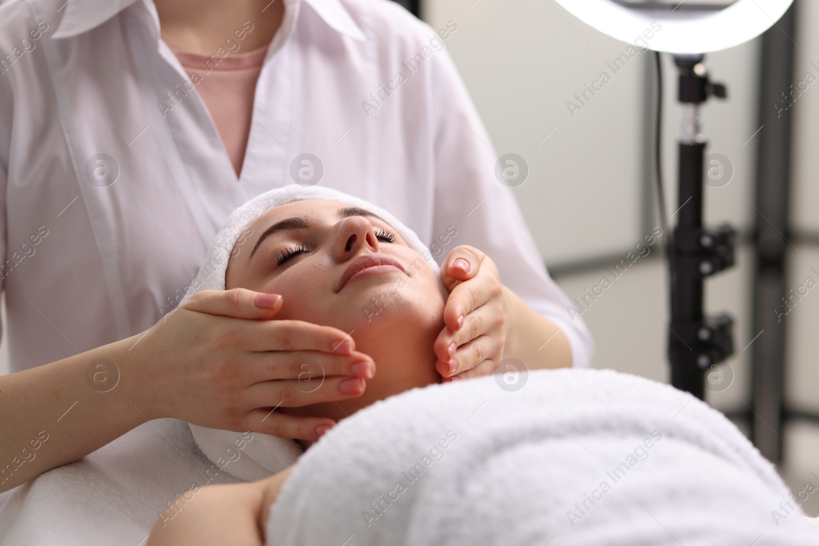 Photo of Cosmetologist making face massage to client in clinic, closeup