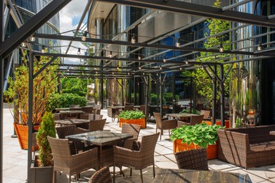 Photo of Beautiful cafe with stylish furniture and plants outdoors