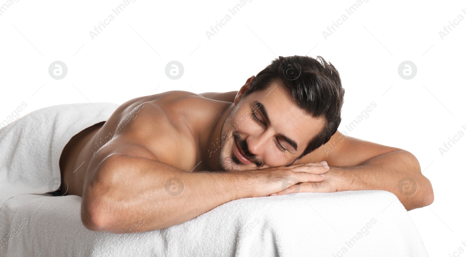 Photo of Handsome young man relaxing on massage table against white background. Spa salon