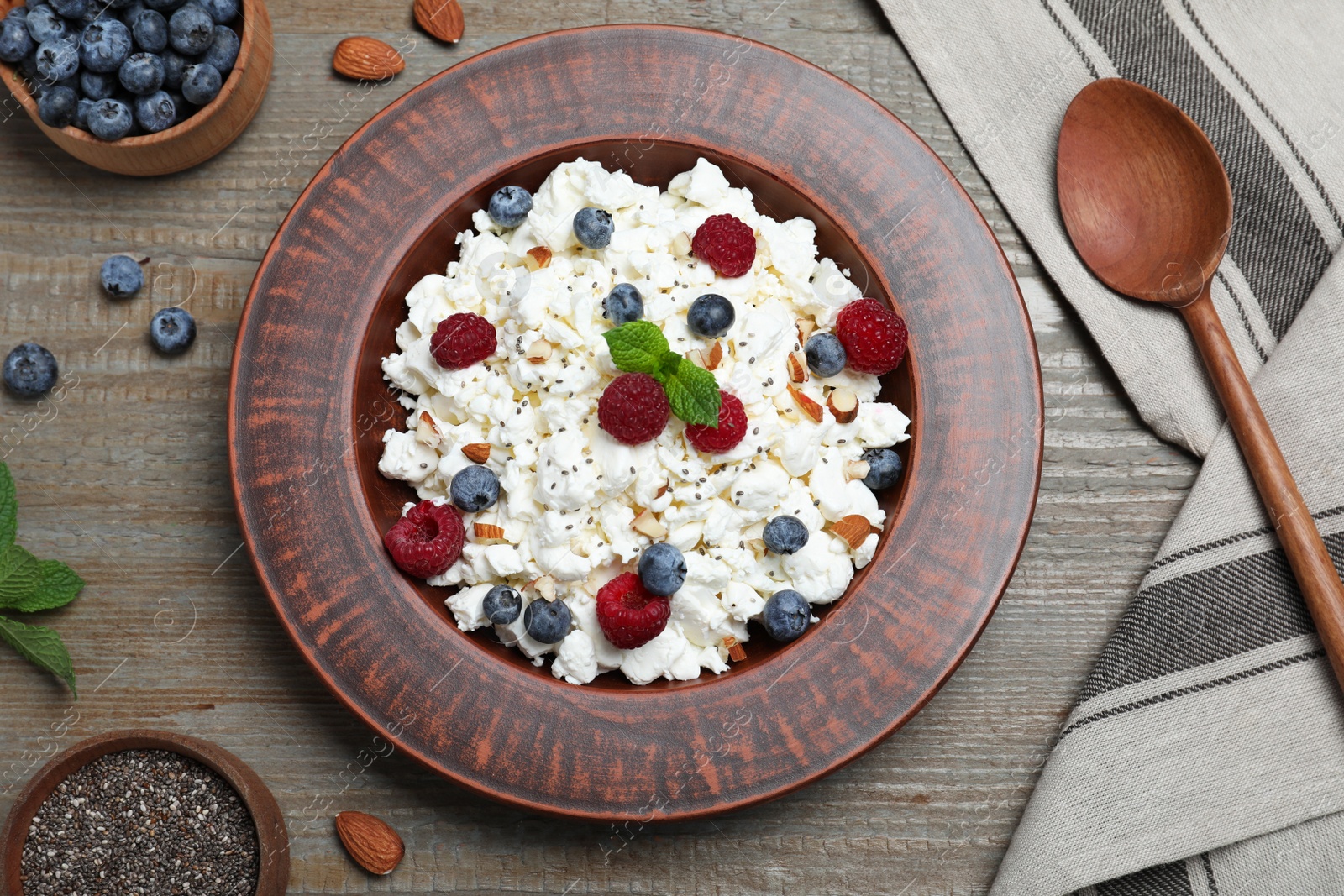 Photo of Fresh cottage cheese with berries and mint in plate on wooden table, flat lay