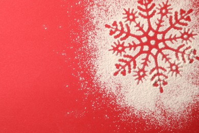 Photo of Snowflake silhouette made with artificial snow on red background, top view. Space for text
