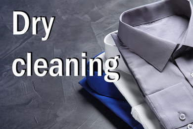 Stylish shirts on grey stone table and inscription Dry Cleaning 