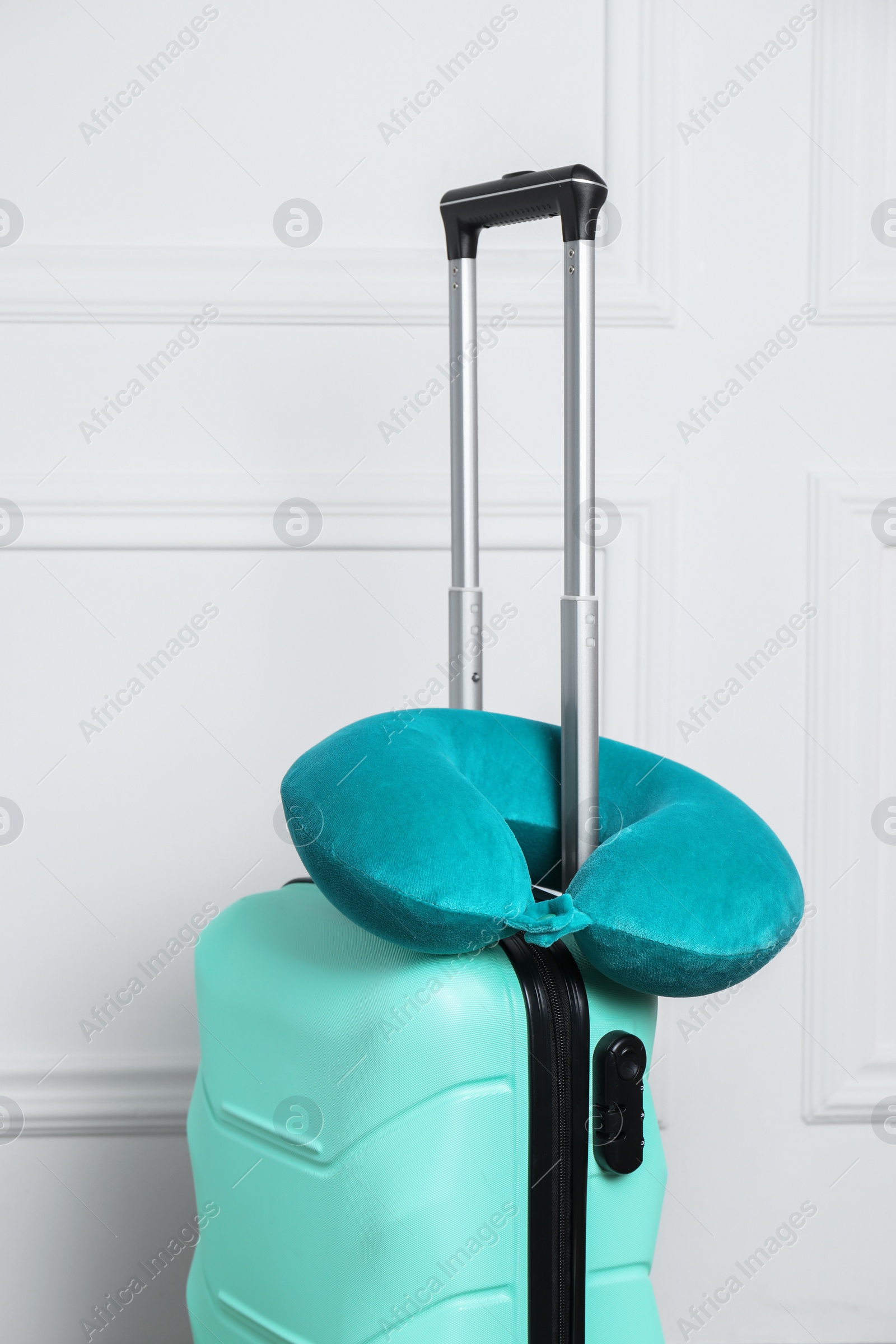 Photo of Turquoise travel pillow on suitcase near white wall